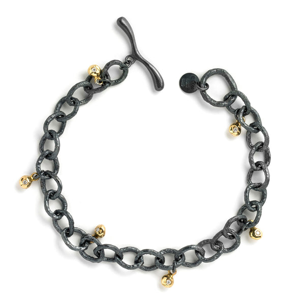 The InsideOut textured links bracelet in blackened sterling silver is adorned with small, shiny 18k yellow gold elements, featuring a delicate diamond. These dangling gold elements add a playful flare to the dark aesthetic of the bracelet, creating an eye-catching contrast and making it a stylish accessory for any occasion.  • Blackened sterling silver, 18k yellow gold, diamonds 0.09 cts
