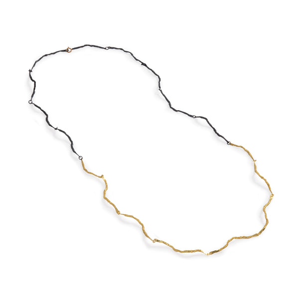 The Mystic Long Black & Gold Necklace by Emanuela Duca - A stunning long necklace crafted in 18k yellow gold and blackened sterling silver. Its intricate texture and contrasting metals create a captivating allure. Whether worn solo or layered, it promises to infuse every moment with a touch of enchantment and sophistication.