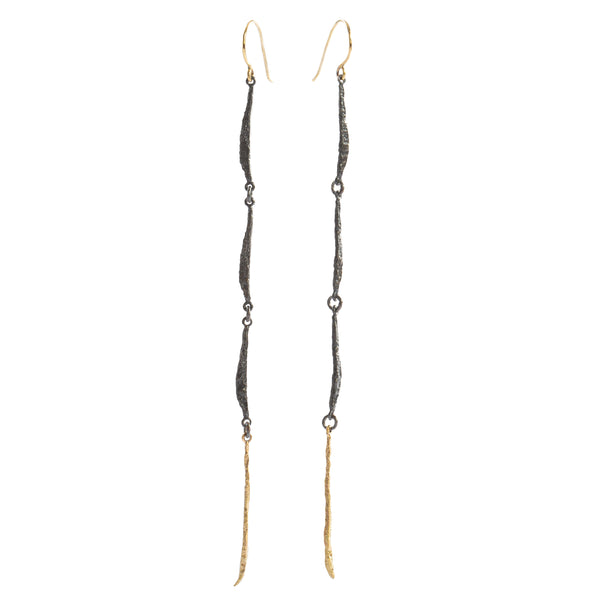 The Spark & Soul long earring features a fluid design, combining sterling silver and 18k yellow gold. This elegant piece makes a statement of femininity. • Blacked sterling silver, 18k yellow gold • Length: 3"
