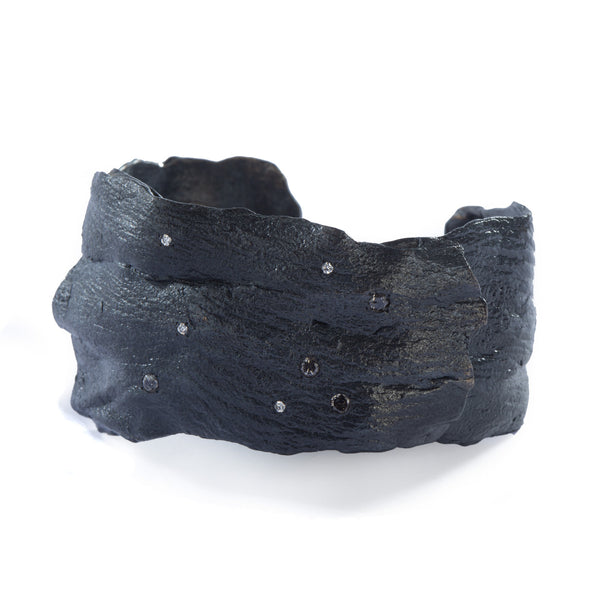 The Spark & Soul cuff in blackened sterling silver, adorned with small diamonds, is a true wearable sculpture. It evokes the feel of a dark night sky illuminated by stars, being both dark and radiant. • Blackened sterling silver, diamonds 0.46 cts • Width: 1.60"