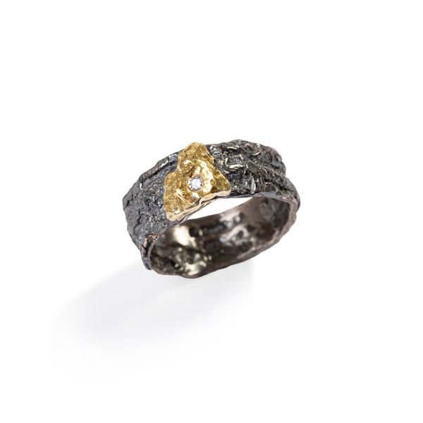 Raw You Black With Gold Ring by Emanuela Duca A fusion of raw sophistication and modern elegance. Crafted from textured blackened sterling silver, it features a 2mm diamond set against raw 18k yellow gold. Embodying contemporary style with a touch of edge, this piece elevates any ensemble with its unique allure.