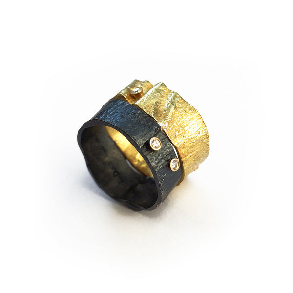 The Under a Tree ring is a stunning and unique piece designed to capture the essence of nature's beauty. This exquisite ring features a beautifully textured 18k yellow gold surface that contrasts strikingly with blackened sterling silver, reminiscent of the vibrant energy of a majestic tree. Adorned with three petite diamonds, it brings a bright sparkle that enhances its elegant design.