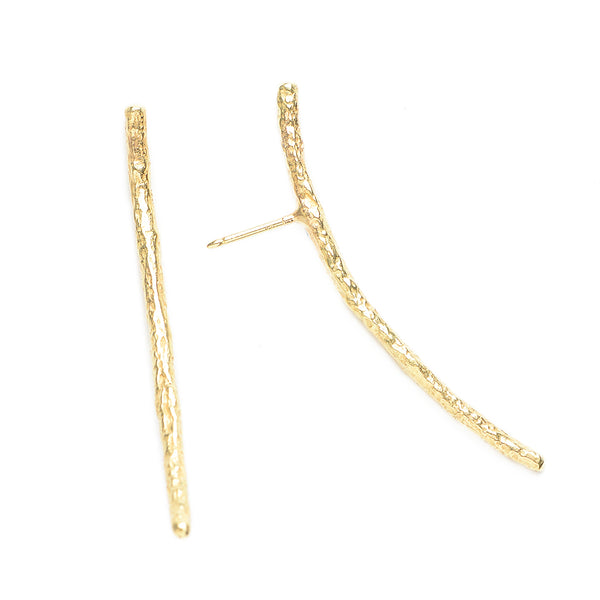 The Under a Tree earrings is a pair of elegantly designed accessories that exude simplicity and character. They feature a gently curved bar crafted from textured 18k yellow gold, capturing the essence of natural beauty with a refined touch. The minimalist design ensures versatility, making these earrings perfect for both everyday wear and special occasions. • 18k yellow gold • Length: 1.75"