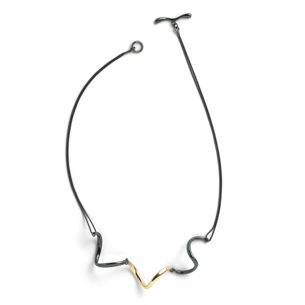 The InsideOut necklace features curved elements in blackened sterling silver, contrasting with a striking 18k yellow gold accent. Held by a double blackened sterling chain, its fluid and elegant design evokes the grace of a beautiful dance.  • Blackened sterling silver, 18k yellow gold  • Length: 18.5"