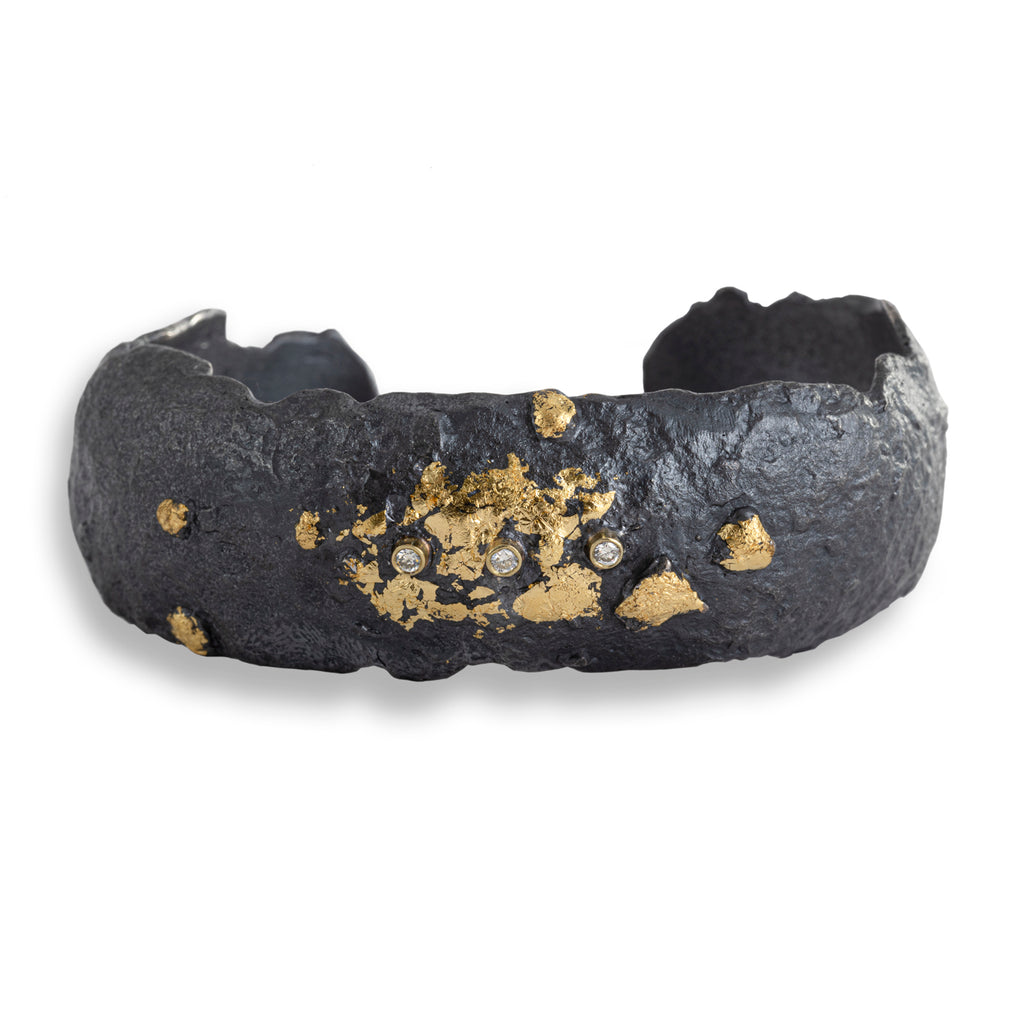 The November's Moon cuff showcases an intriguing design, with an 18k yellow gold leaf set against blackened sterling silver and accented by three 2mm diamonds in gold bezels. This combination exudes an earthy yet edgy contemporary style that's both bold and captivating.&nbsp;  • Diamond ct: 0.09
