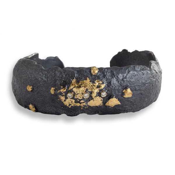 The November's Moon cuff showcases an intriguing design, with an 18k yellow gold leaf set against blackened sterling silver and accented by three 2mm diamonds in gold bezels. This combination exudes an earthy yet edgy contemporary style that's both bold and captivating.&nbsp;  • Diamond ct: 0.09