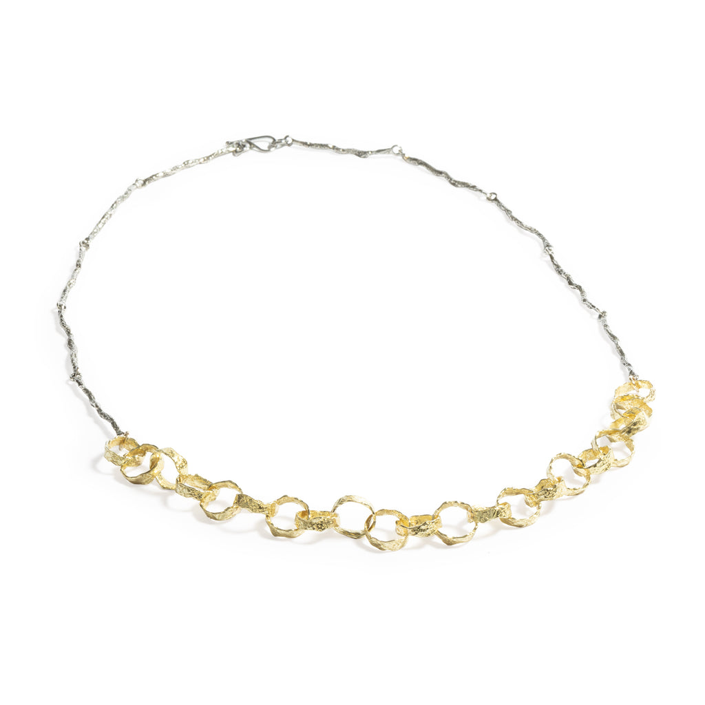 Good Vibes Black  & Gold Necklace by Emanuela Duca - Crafted with meticulous attention to detail, this necklace features a centerpiece of textured 18K yellow gold flattered links, perfectly complemented by a textured blackened sterling silver chain. Whether worn alone as a focal point or layered for a more eclectic look, this piece radiates positivity and creativity. Elevate your style with its whimsical yet refined design, adding an artistic touch to any ensemble.