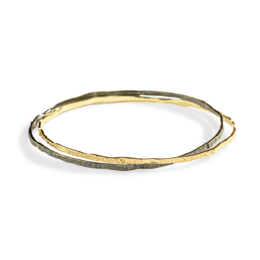 The Mystic Bangle by Emanuela Duca - The Mystic Bangle: a sophisticated fusion of 18k yellow gold and blackened sterling silver, forming two interconnected circles. This intriguing design offers a sophisticated yet versatile look suitable for everyday wear, adding a touch of mystique to any ensemble.