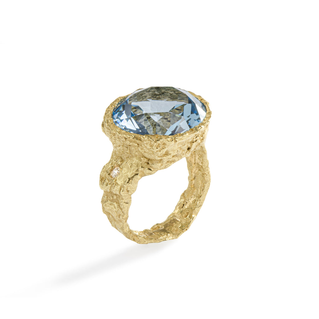 Colibri' Blue Topaz Ring by Emanuela Duca - The Colibri' Ring, crafted in textured 18k yellow gold, showcases a stunning 12mm blue topaz stone paired with a diamond (2mm). The beautiful blue color of the stone complements the warmth of the gold. This piece adds a vital spark to your look, infusing it with energy and elegance. • Blue topaz, diamond, 18k yellow gold