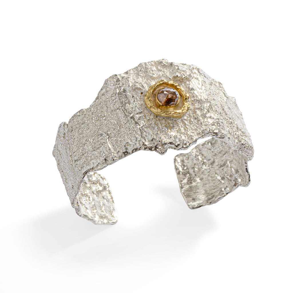 Raw You Silver Cuff by Emanuela Duca - Crafted from intricately textured sterling silver, adorned with an antique rose-cut diamond embraced by an elegant 18k yellow gold accent. This design epitomizes contemporary uniqueness with a raw sophistication, harmonizing light and rawness in perfect contrast.
