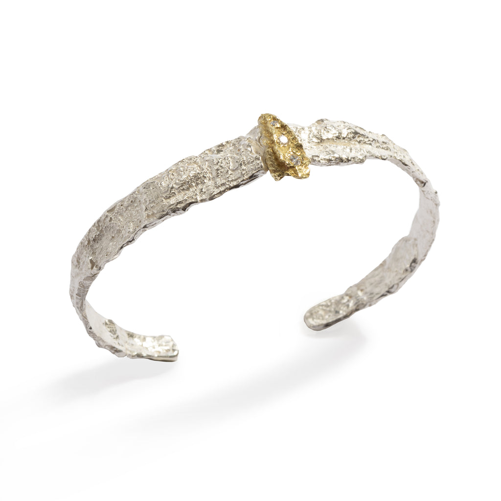 Raw You Small Silver & Gold Cuff by Emanuela Duca - Crafted from textured sterling silver, it's accentuated by an elegant 18k yellow gold element, delicately showcasing three small diamonds. This design embodies a perfect contrast, harmonizing light and rawness, for a truly captivating statement piece.