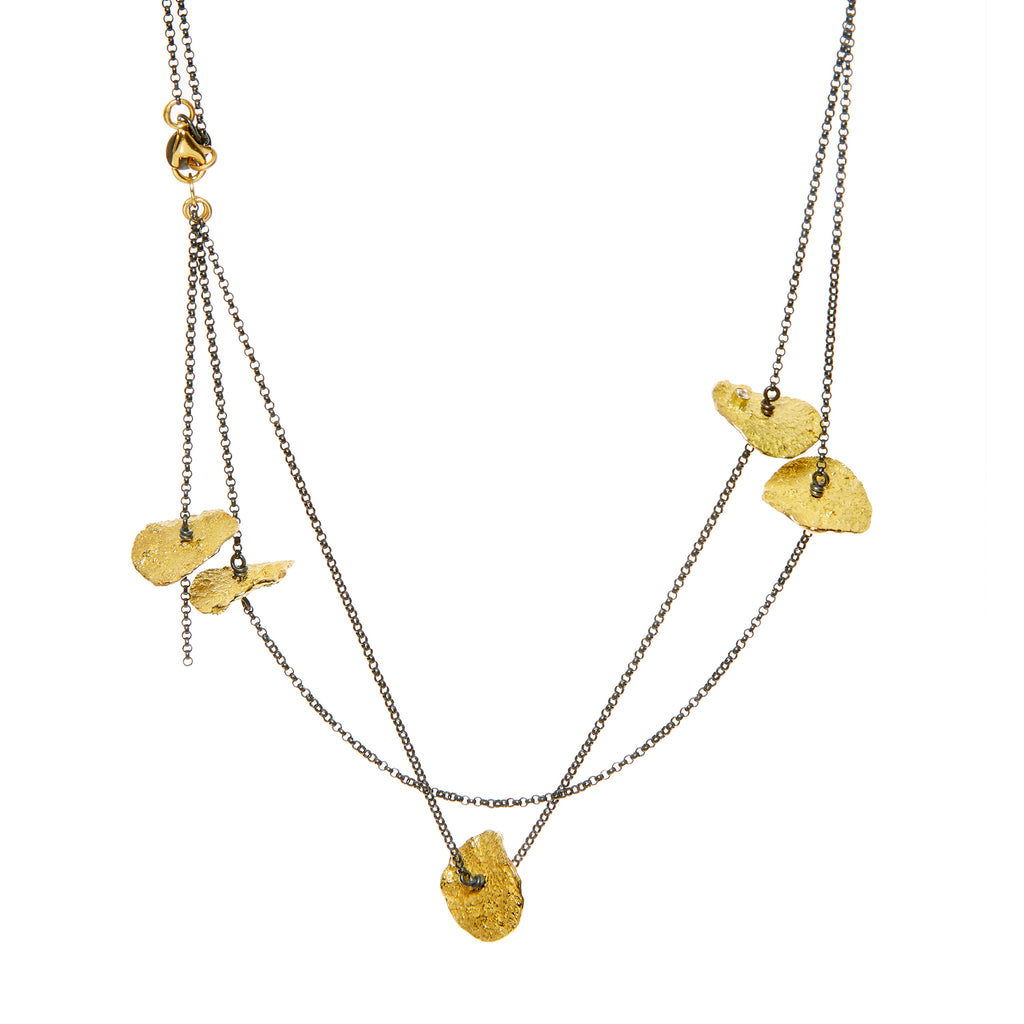 The Floating in the Dark large disc necklace is a striking statement piece that showcases bold personality. Accented by diamonds set in 18k yellow gold, this necklace combines the dramatic allure of large discs with the luxurious sparkle of diamonds and the warmth of gold, making it a standout accessory.  • Blackened sterling silver, 18k yellow gold chain, diamonds ct: 0.12
