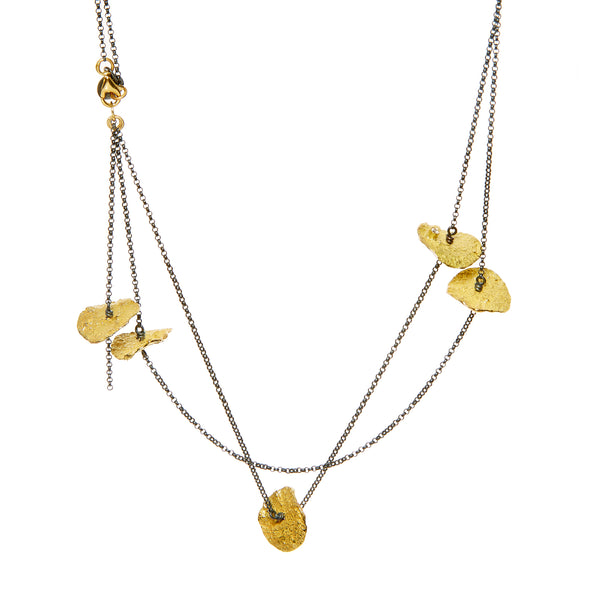 The Floating in the Dark large disc necklace is a striking statement piece that showcases bold personality. Accented by diamonds set in 18k yellow gold, this necklace combines the dramatic allure of large discs with the luxurious sparkle of diamonds and the warmth of gold, making it a standout accessory.  • Blackened sterling silver, 18k yellow gold chain, diamonds ct: 0.12